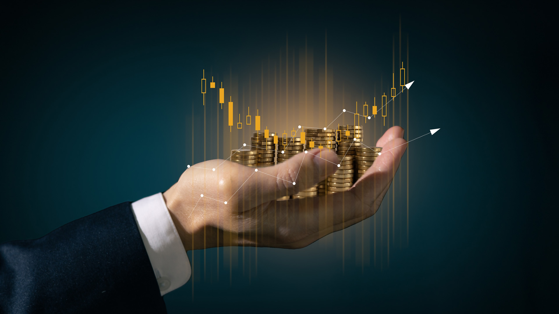 Hand holding coins with financial candle stick chart in background